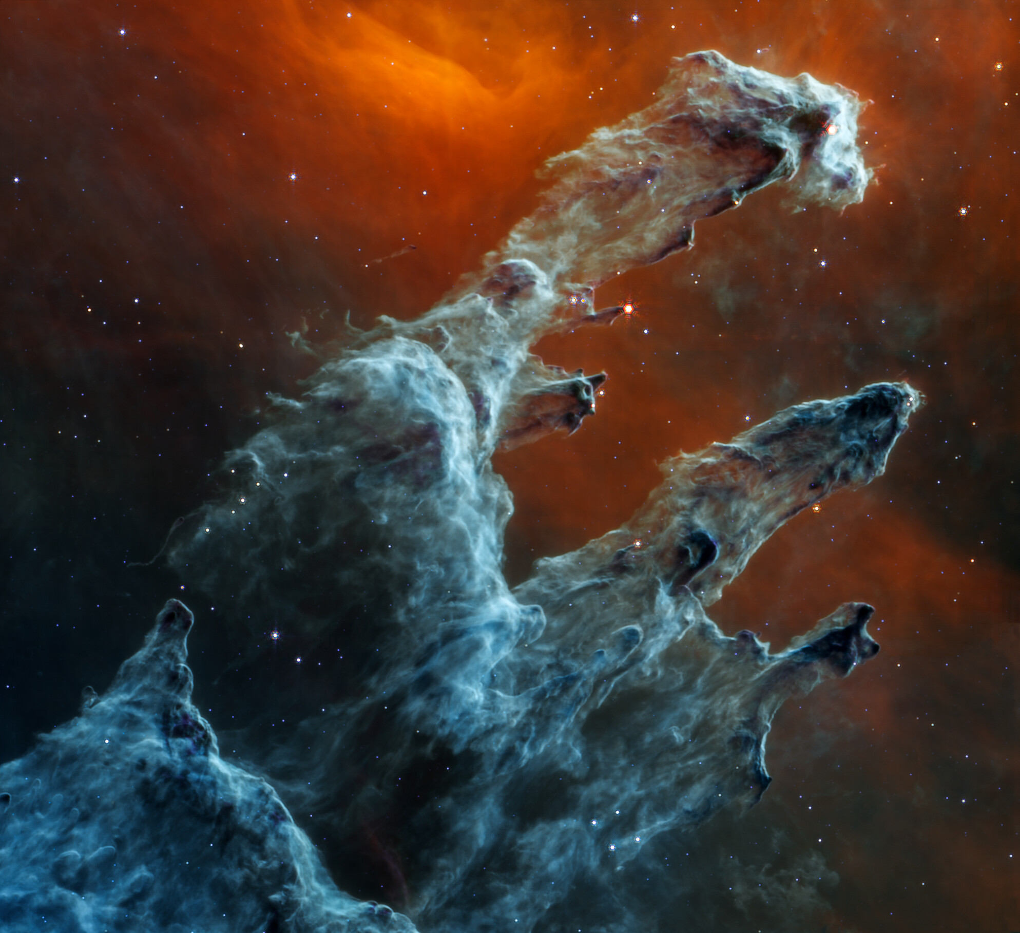 Blue-gray gas-and-dust pillars rise against an orange background in Webb’s mid-infrared observation, with far fewer prominent stars than in the near-infrared view.