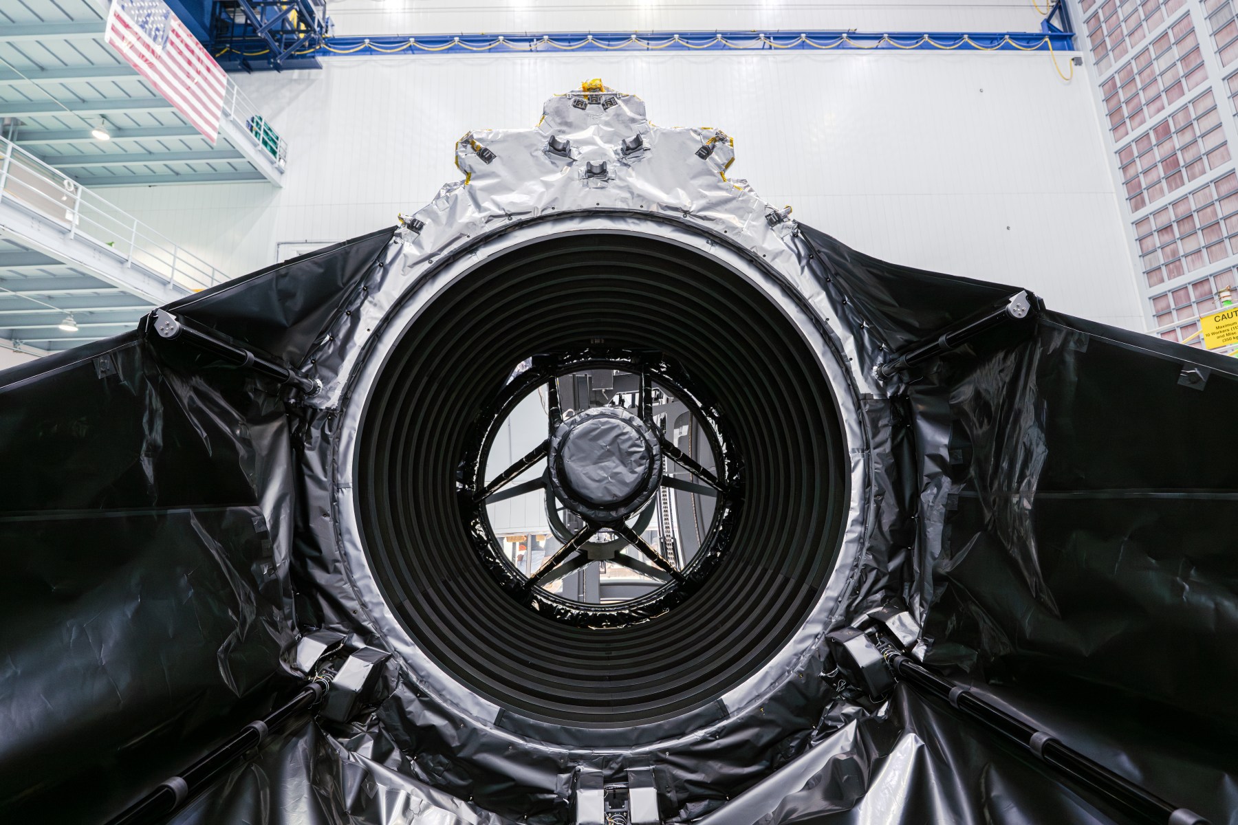 The circular opening of the Roman telescope, surrounded by black and silver insulation in a clean room.