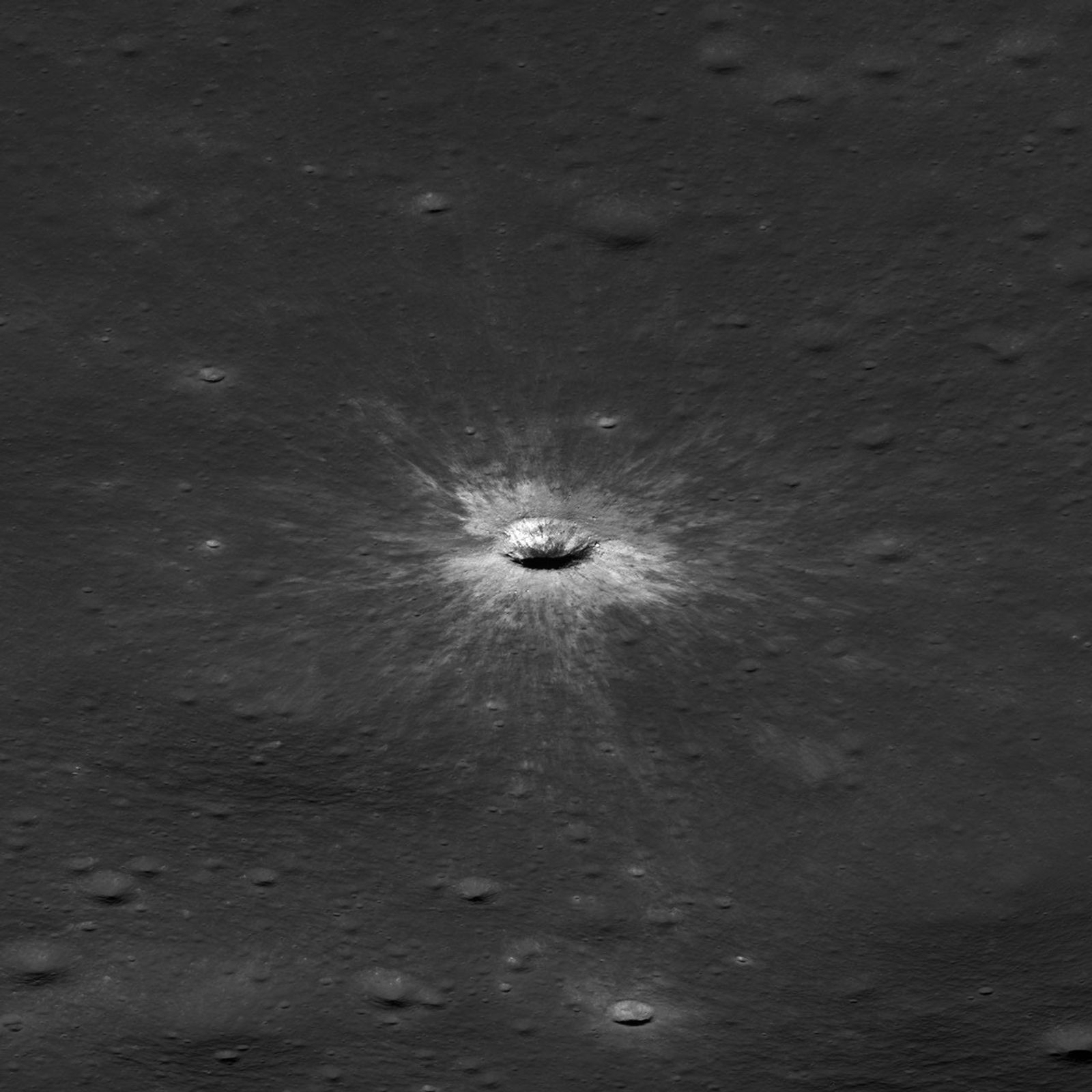 An oblique lunar view shows the crater rim and rays across surrounding terrain.