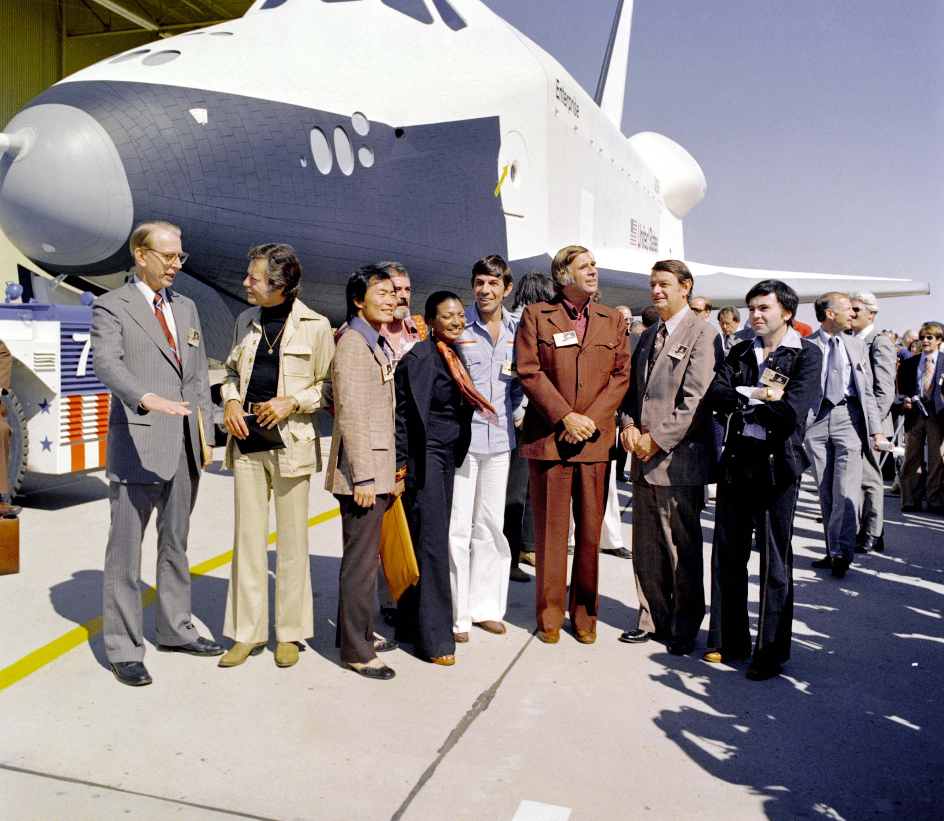 Star Trek cast members and NASA officials stand in front of the shuttle Enterprise.